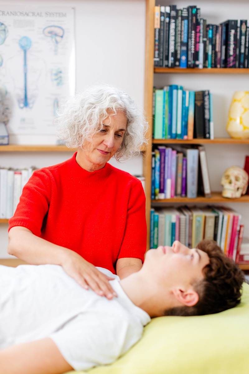 A CranioSacral Therapy session in progress: light hands-on contact, client fully clothed.